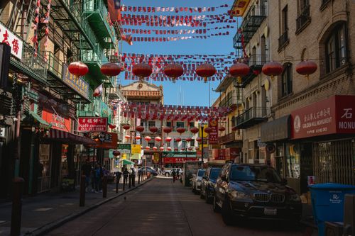 Free Vibrant Chinatown street with red lanterns and cultural signs under a sunny sky. Stock Photo