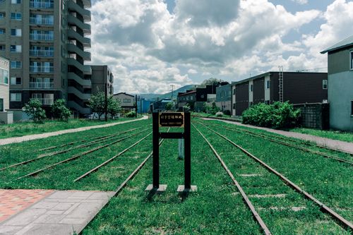 Free An old railway track amidst urban buildings in Hokkaido, Japan under a cloudy sky. Stock Photo