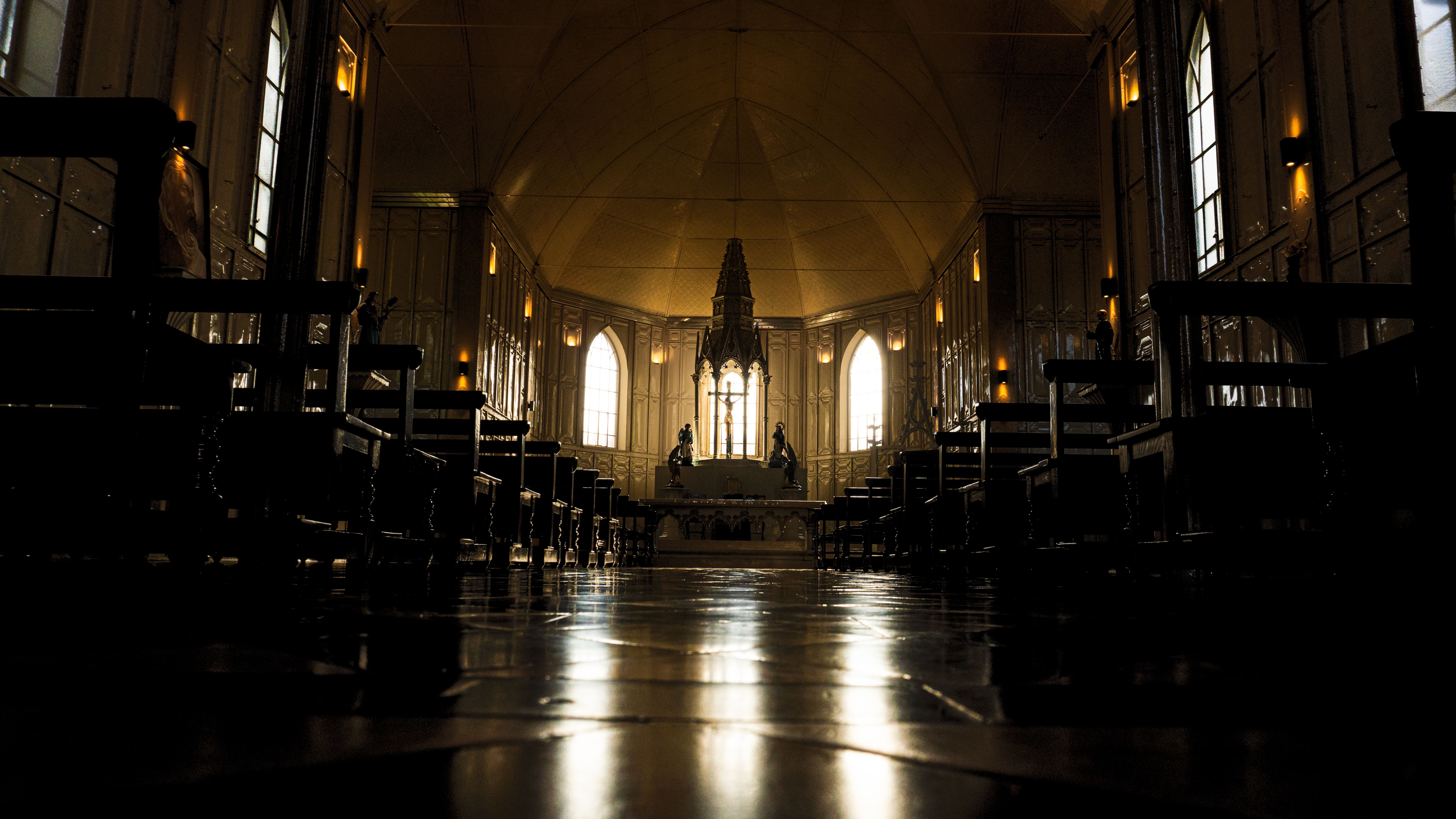 Dramatic view of a gothic cathedral interior with rows of benches and altar.