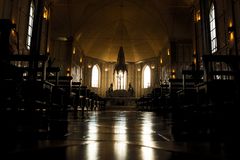 Dramatic view of a gothic cathedral interior with rows of benches and altar.