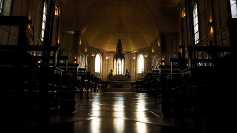 Dramatic view of a gothic cathedral interior with rows of benches and altar.