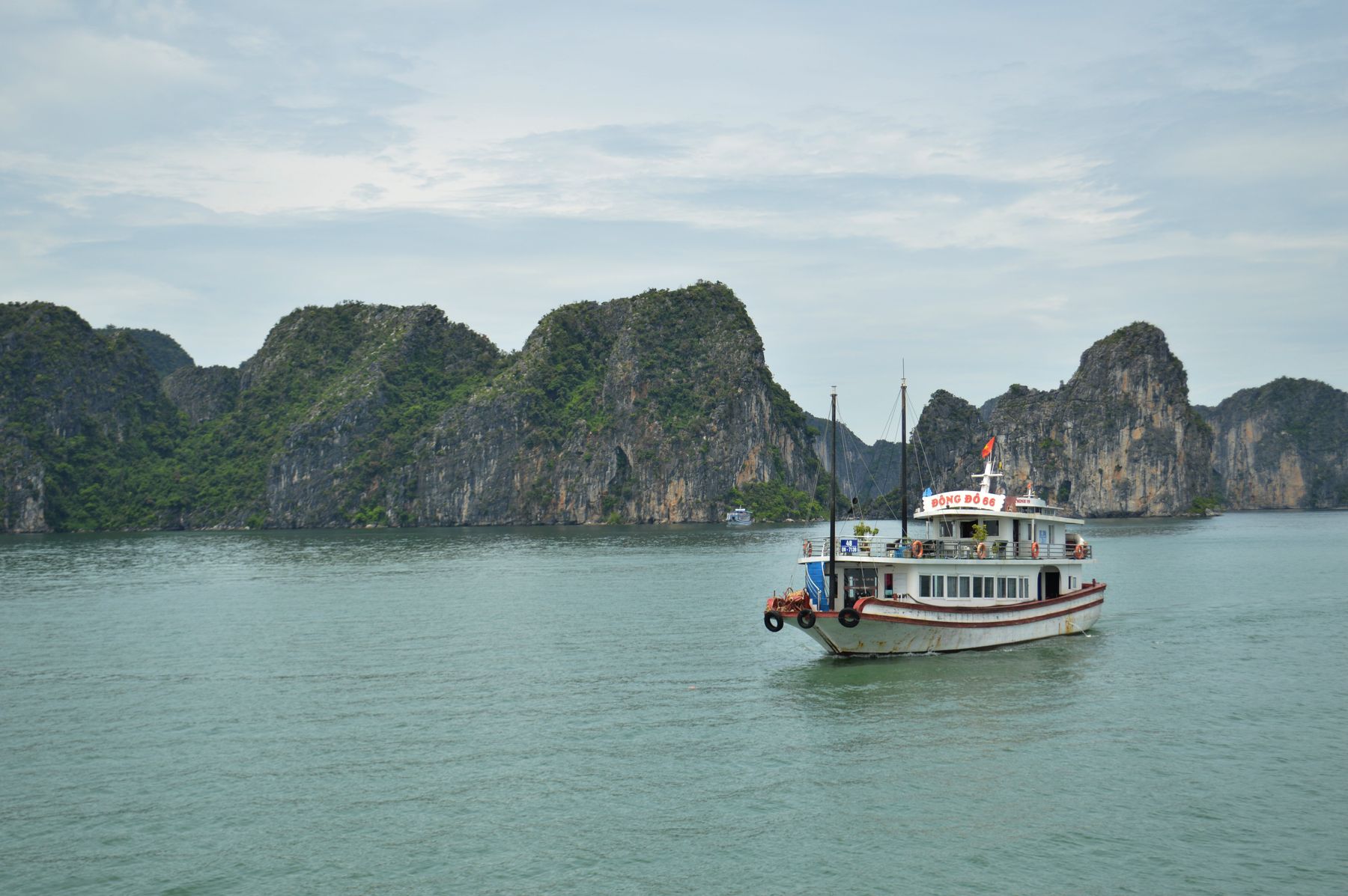 Tour boat crossing Ha Long Bay beneath Vietnam's limestone islands