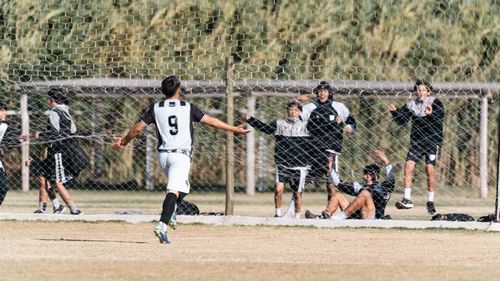 Free A young soccer player celebrates a goal as teammates cheer enthusiastically from the sidelines. Stock Photo
