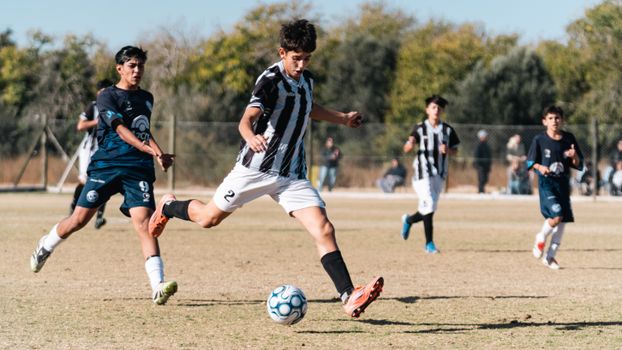 Dynamic action shot of teenagers playing soccer on an outdoor field.