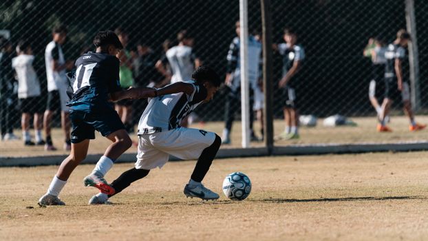 Players compete in an outdoor soccer match on a sunny day. Action-packed and energetic scene.