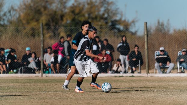 Players in action during a competitive soccer match with crowd watching eagerly.