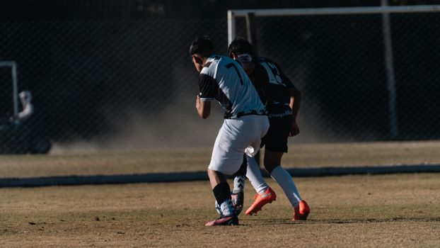 Two soccer players competing on a field during a daytime match.