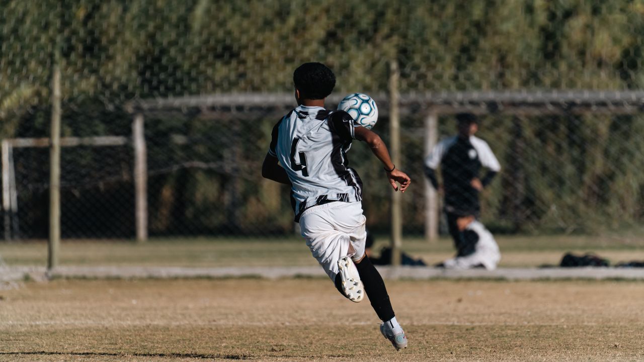 a young soccer player heads a ball during a game on a sunny outdoor fi