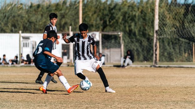 Dynamic photo of teenagers playing soccer on a sunny day, showcasing agility and teamwork.