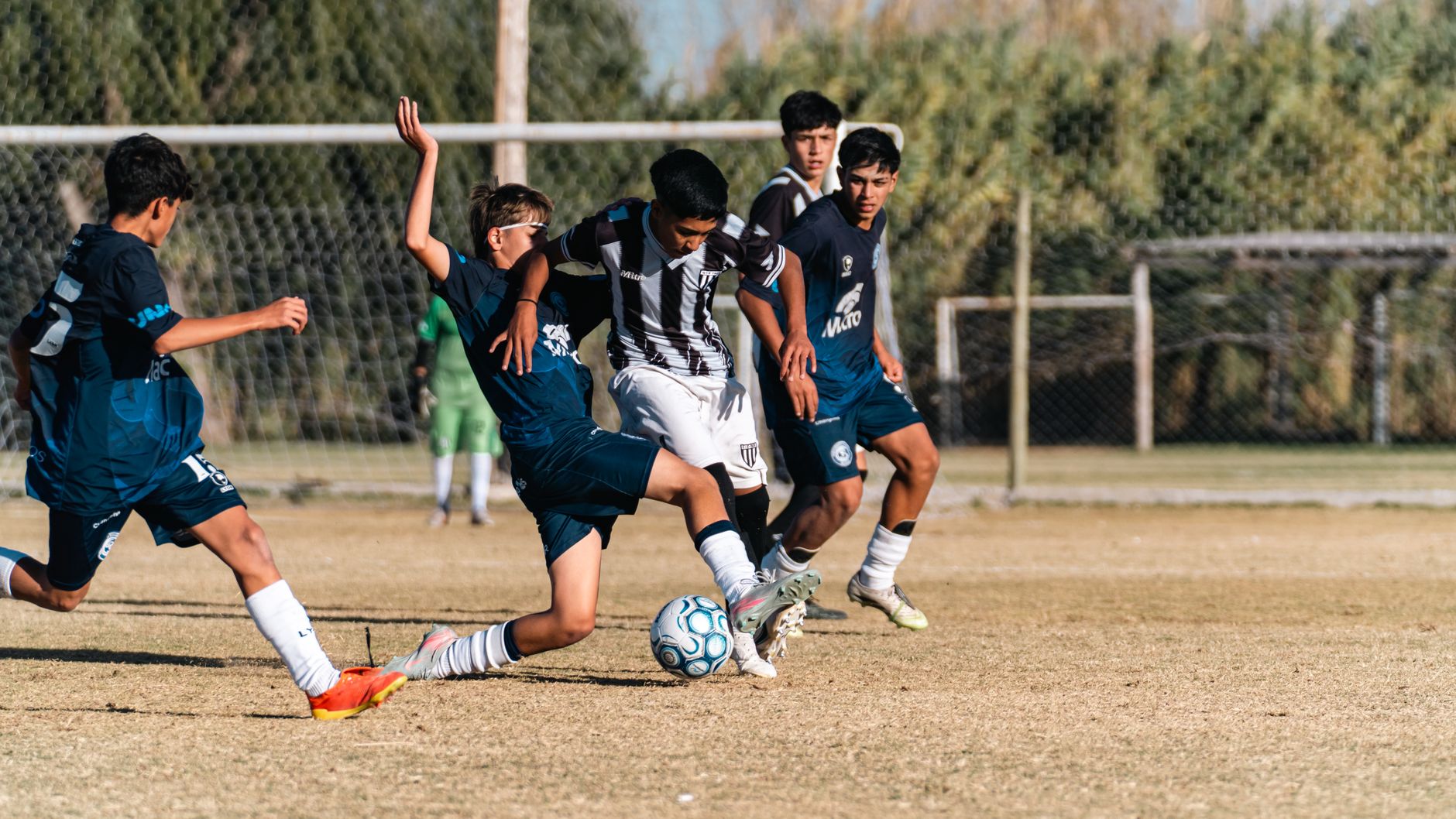 youth football defenders organizing inside the penalty area before a corner kick, coach watching from touchline