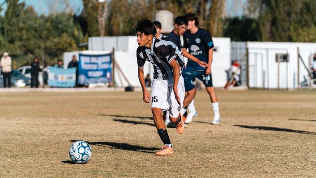 A teenager in a soccer match, focused on the ball and ready to make a strategic play outdoors.
