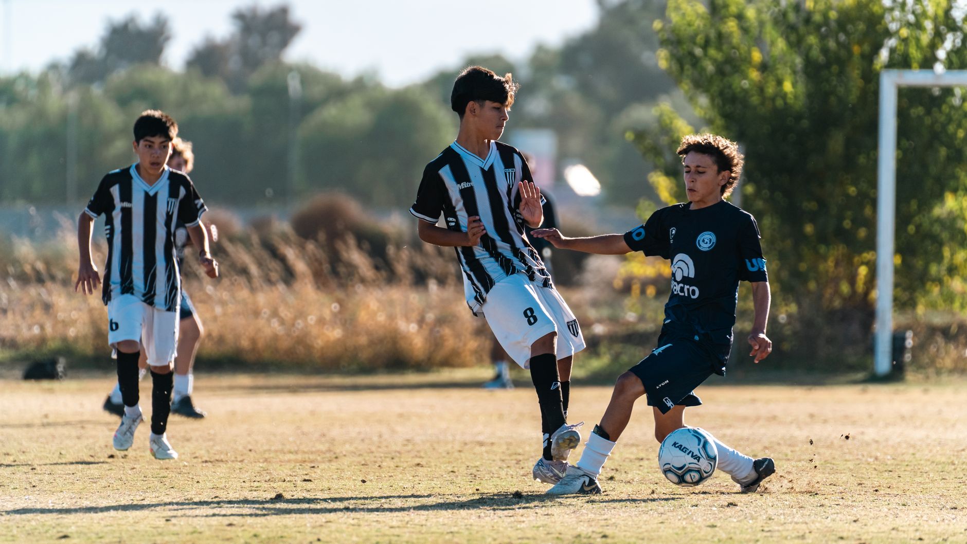 Two teenage soccer players in competitive action during a game on a sunny day.