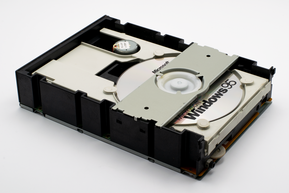 Visão aproximada de uma unidade de CD-ROM antiga contendo um disco do Windows 95, demonstrando a tecnologia retrô.