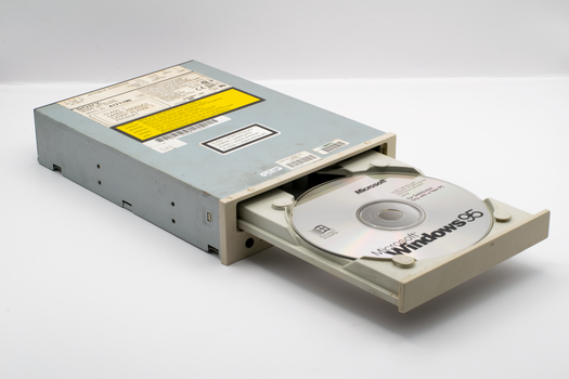 Vintage CD-ROM drive with Microsoft Windows 95 disc, iconic retro tech.