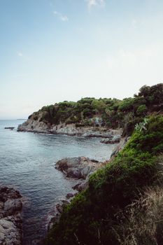 Serene coastal landscape of Lloret de Mar, capturing lush greenery and rocky shores under a clear sky.