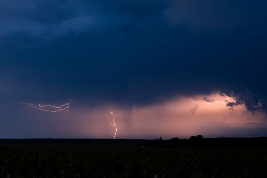 A powerful thunderstorm with vivid lightning strikes over a rural landscape at twilight, capturing the intensity of nature.