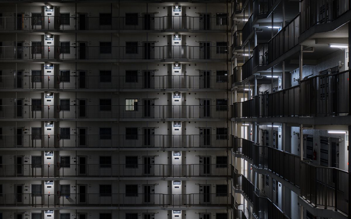 夜に廊下の灯りがともる集合住宅の外観（イメージ）