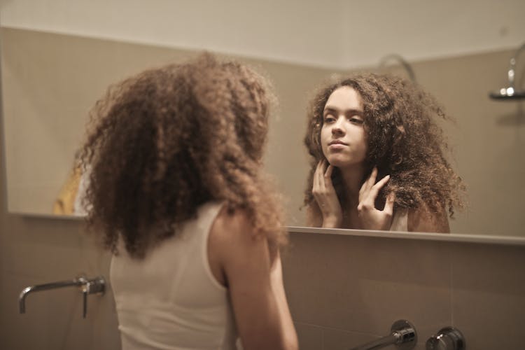 Woman In White Tank Top While Looking Herself At A Mirror