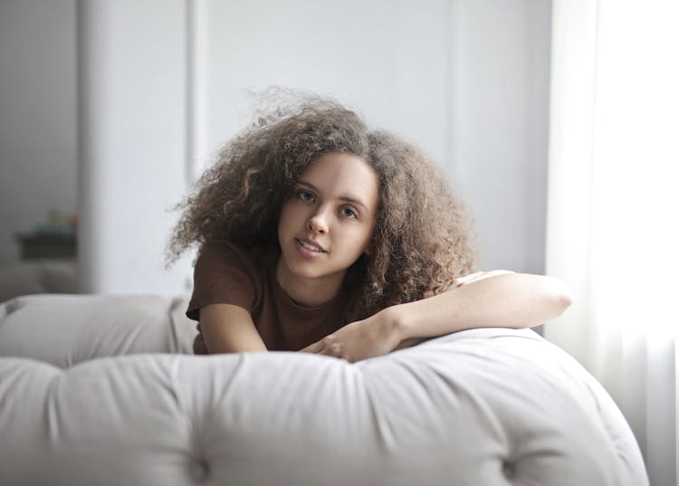 Woman In Brown Top Leaning On White Couch