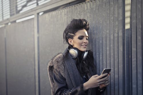 Free Woman in Black and Brown Fur Coat Wearing Black Headphones Stock Photo