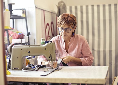 무료 재봉틀을 사용하는 여성의 사진 스톡 사진
