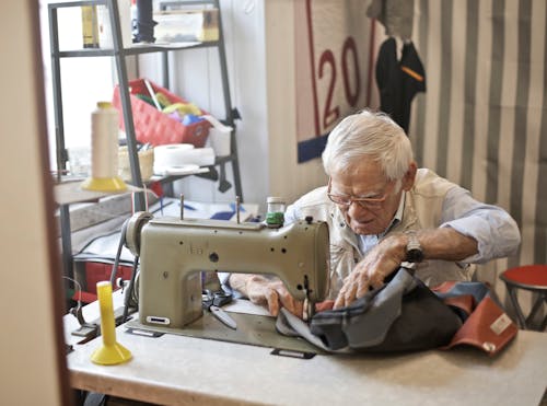 Man in Eyeglasses and Long Sleeve Shirt Sewing