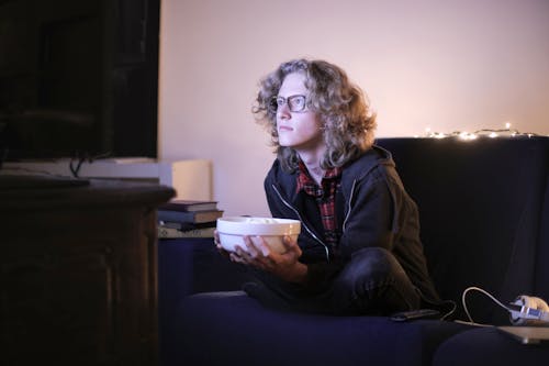 Free Man with a Bowl of Popcorn Watching TV at Home Stock Photo
