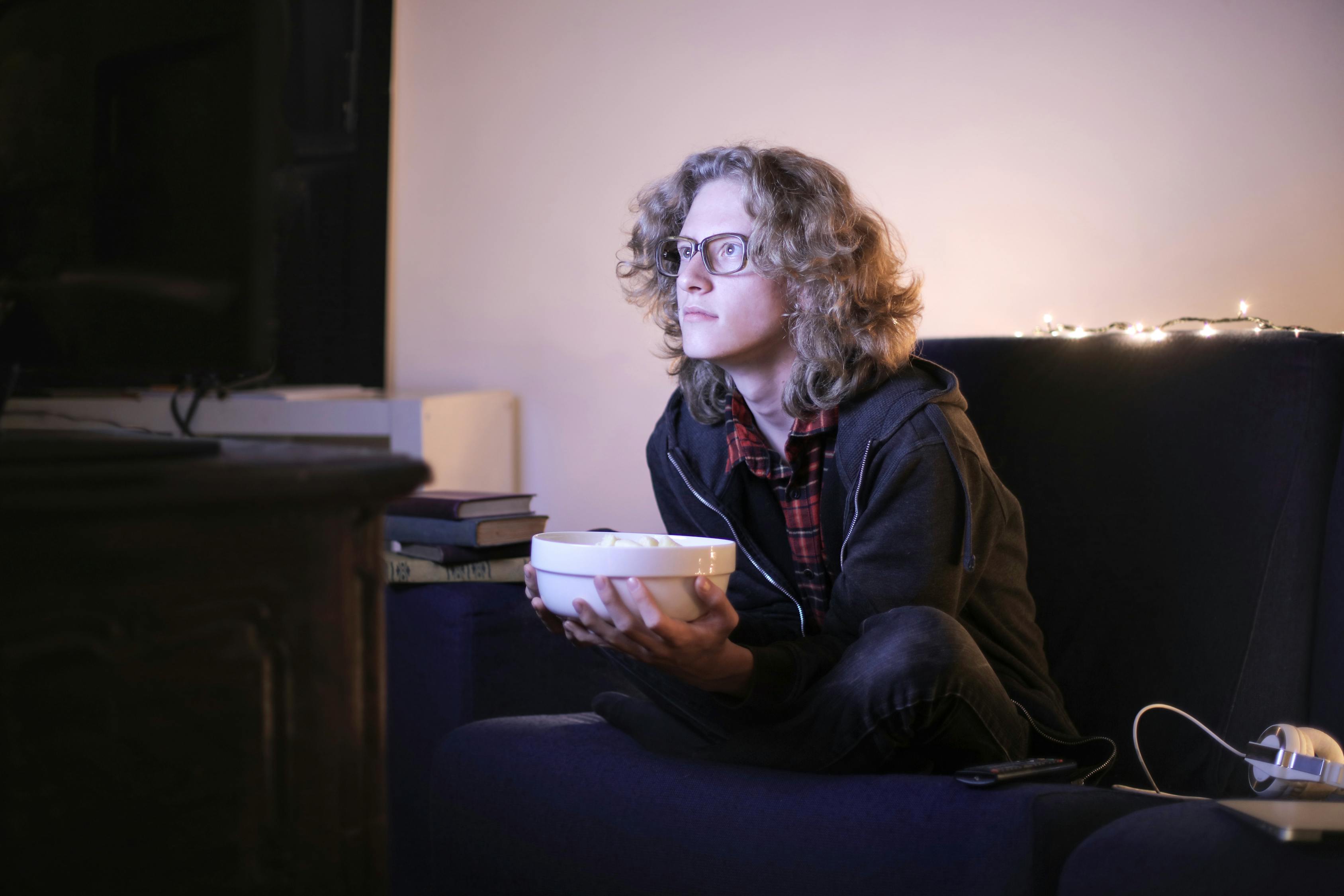 Focused man with bowl of popcorn watching TV at home