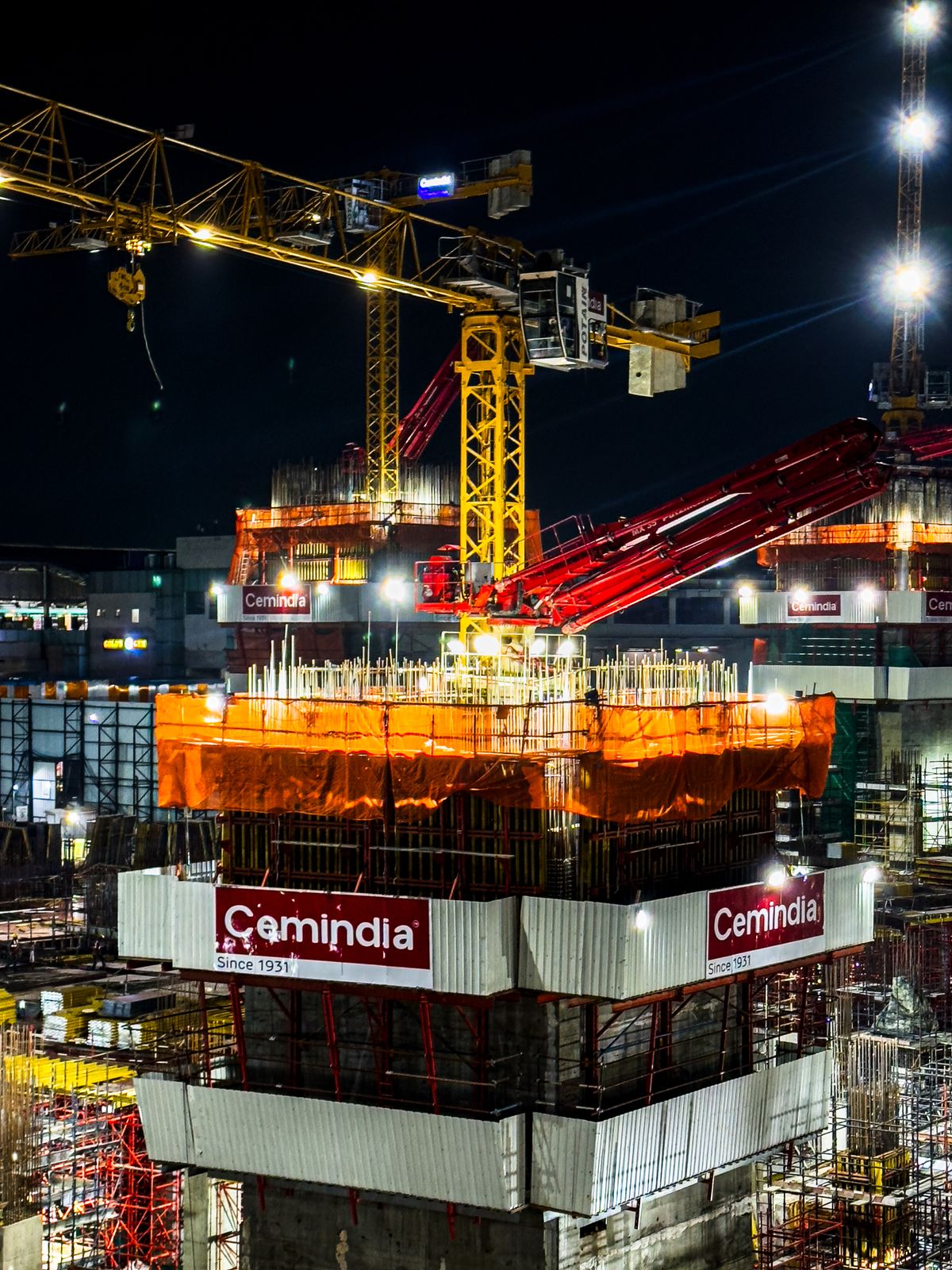 Urban construction site at night with tower cranes working under temporary site lighting