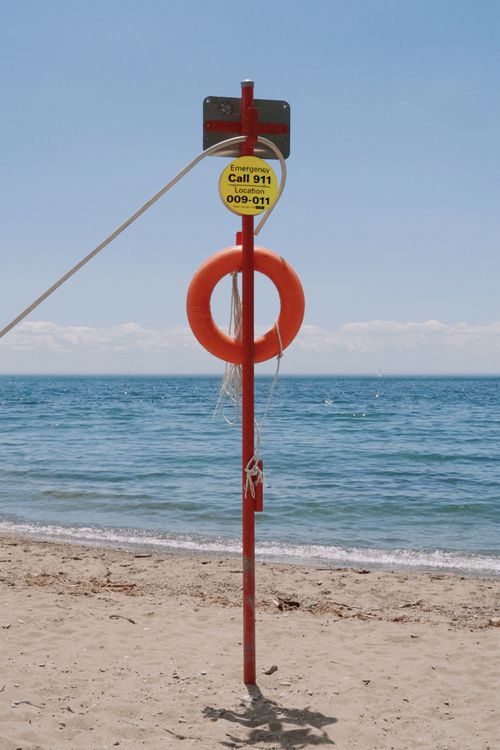 Free Lifesaving equipment on a sandy beach with clear blue water in Toronto. Stock Photo