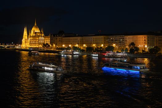 Stunning nighttime view of Budapest Parliament and boats on the Danube River.