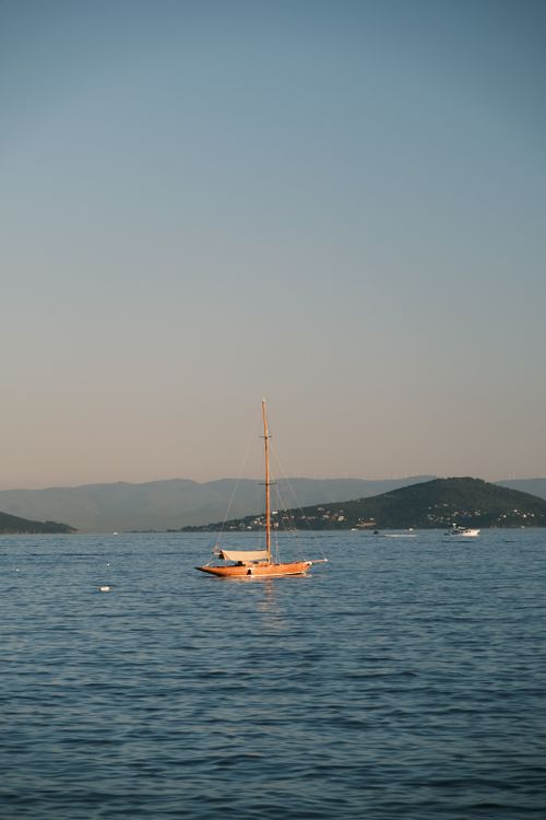 Free A peaceful sailboat on the Bosphorus with a serene backdrop of hills at dusk in İstanbul. Stock Photo