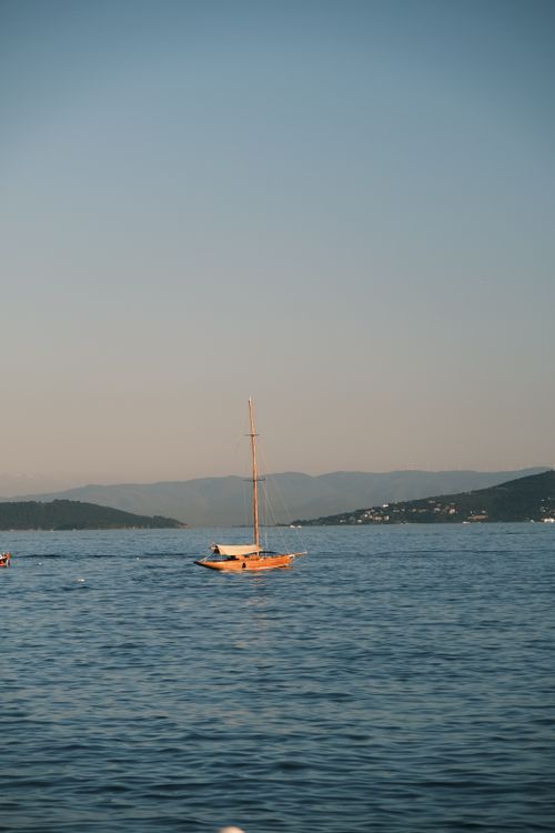 Free A sailboat gently glides across the Bosphorus in Istanbul, Türkiye, at sunset. Stock Photo