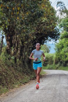 Woman running on a scenic rural road in Pereira, Colombia during daytime.