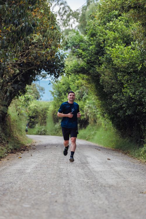 Free A man jogging down a tree-lined path in Pereira, Colombia, emphasizing a healthy lifestyle. Stock Photo