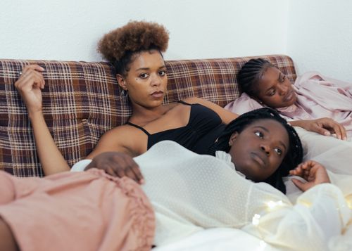 Free Three black women relaxing on a bed in a cozy indoor setting, reflecting a moment of calm and companionship. Stock Photo