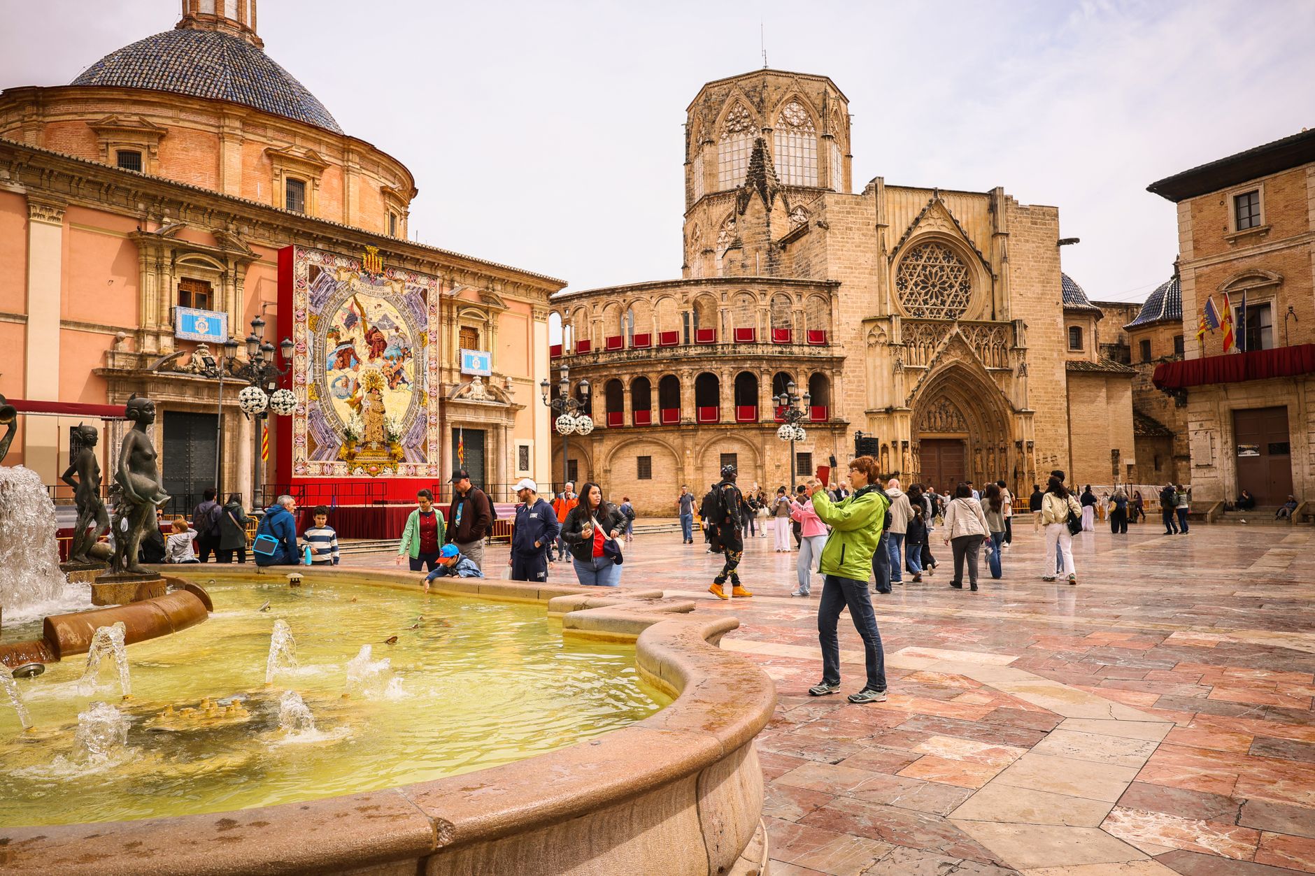 Tourists enjoy a sunny day at the historic Plaza de la Virgen in Valencia, Spain.