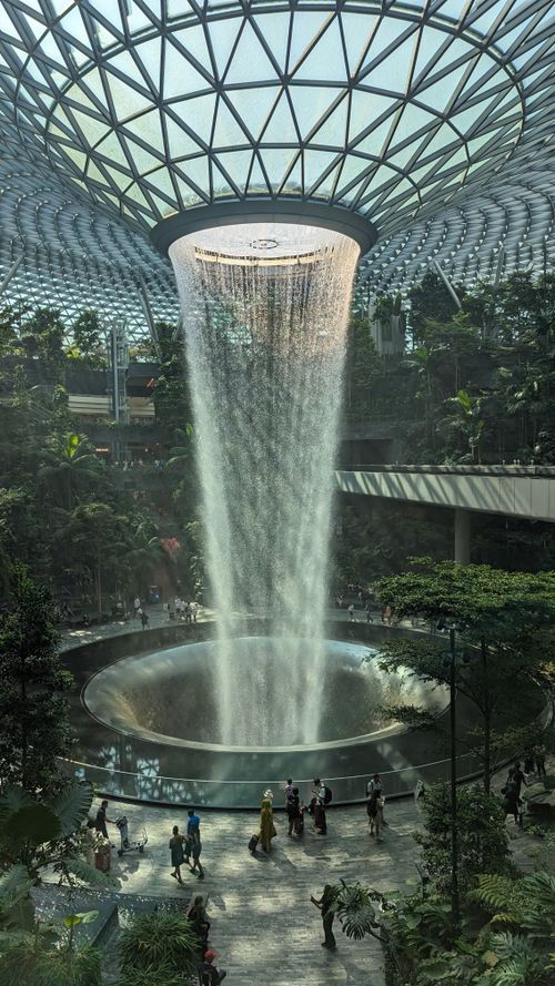 Free Spectacular indoor waterfall at Jewel Changi Airport surrounded by lush greenery. Stock Photo