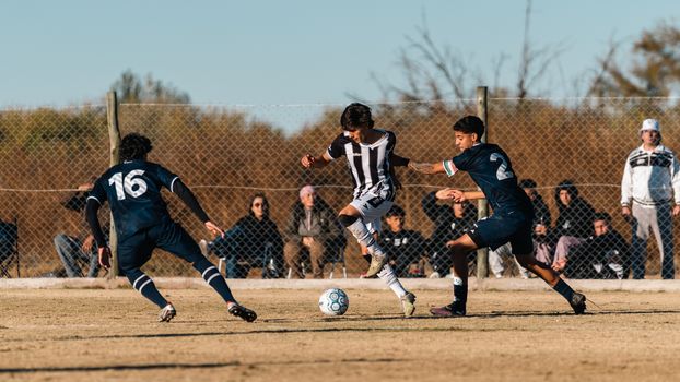 Dynamic young players in a soccer match, showcasing skill and teamwork on a sunny day.