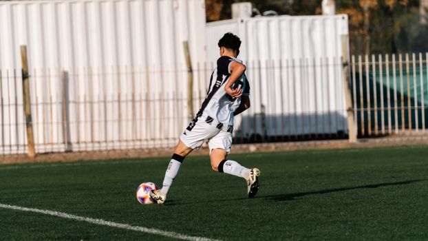 Back view of a young soccer player in motion during a game on a sunny day.