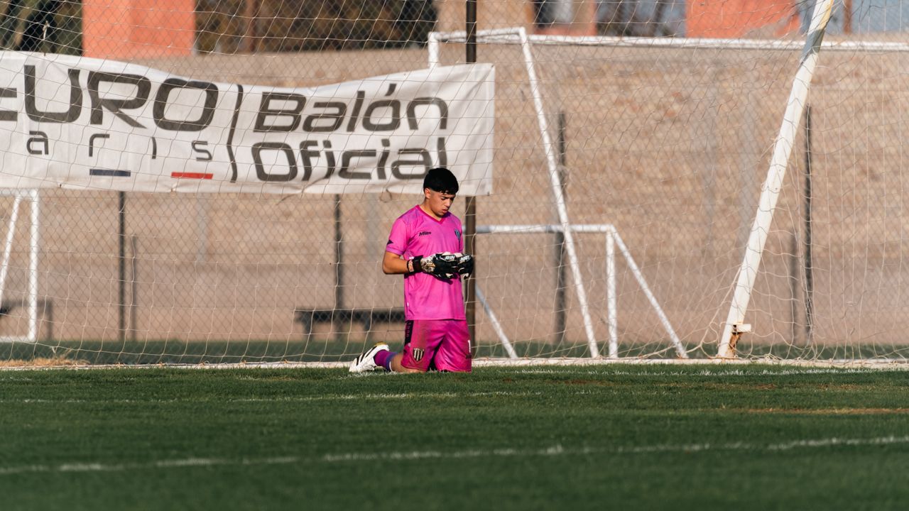 goalkeeper kneeling on field in pink kit during a soccer match outdoor