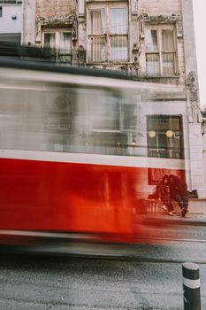 Blurry motion of a red tram passing by in Istanbul, Türkiye. Urban lifestyle scene with historic architecture.