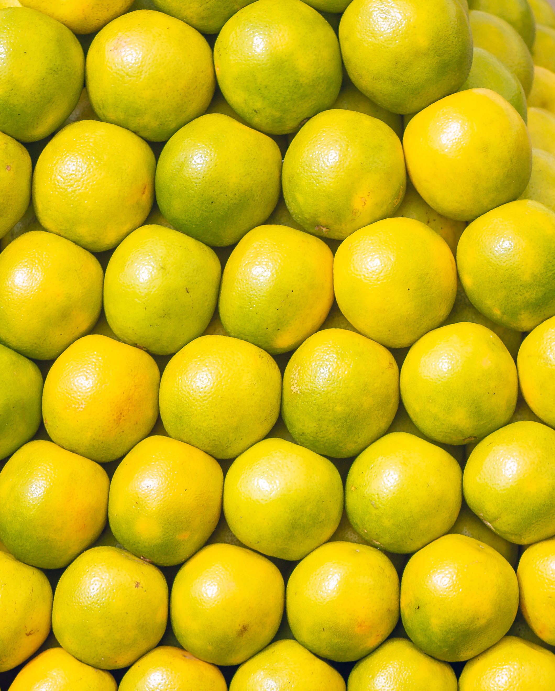 A visually appealing stack of fresh yellow lemons arranged closely together, showcasing their bright and vivid color.