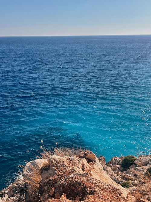 Free Beautiful view of the Mediterranean Sea from a rocky cliff under a clear blue sky. Stock Photo