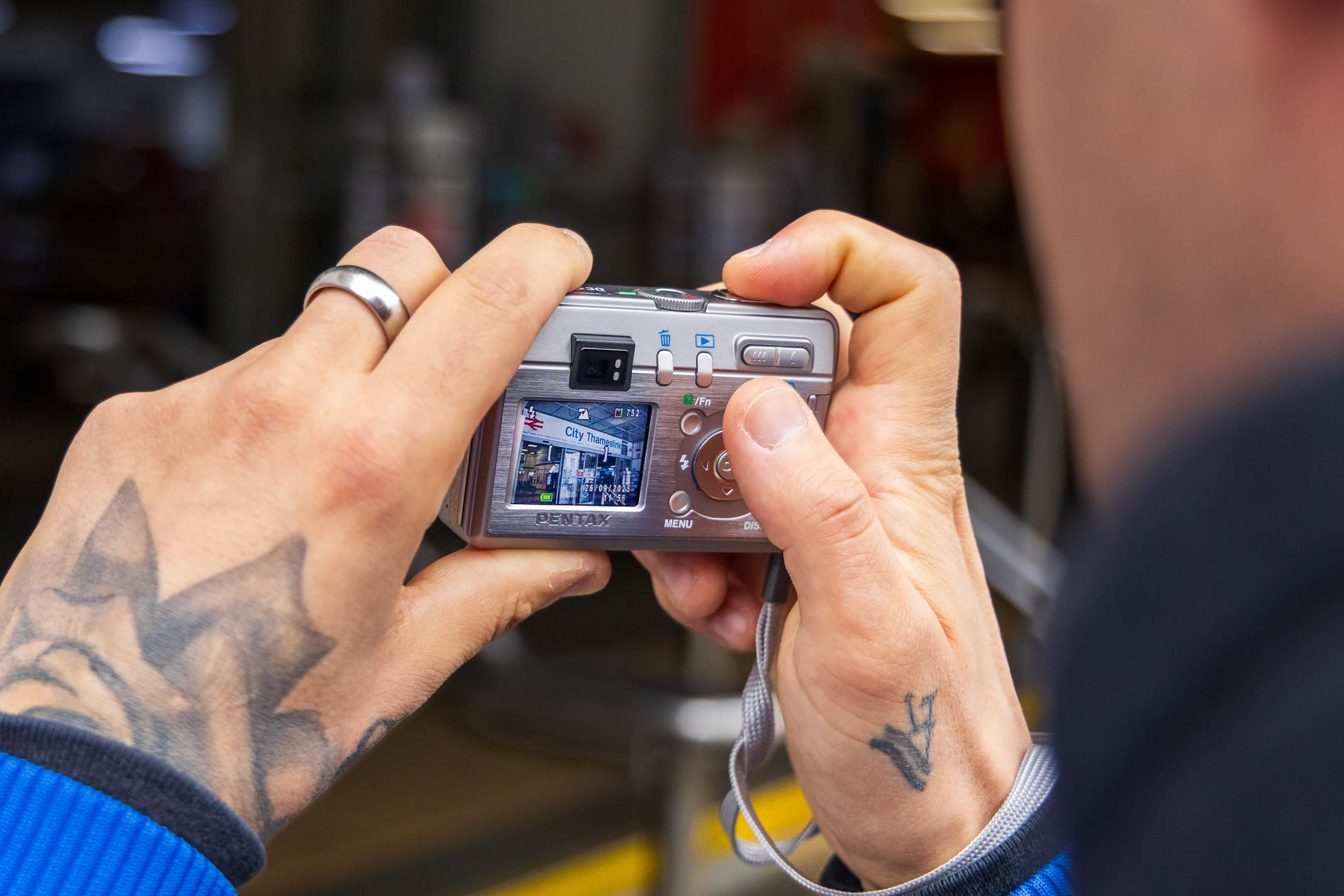 Close-up of a person using a digital camera with a visible screen image.
