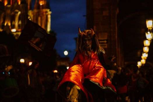 A lively night scene capturing a costumed performer at a colorful festival parade.