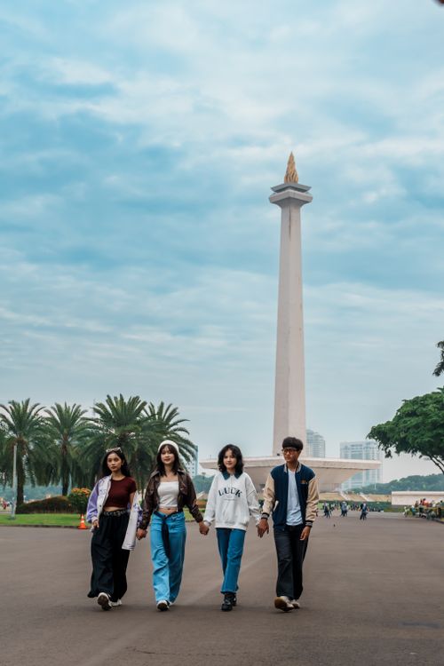 Free Four young adults walking near the National Monument in Jakarta, Indonesia. Stock Photo