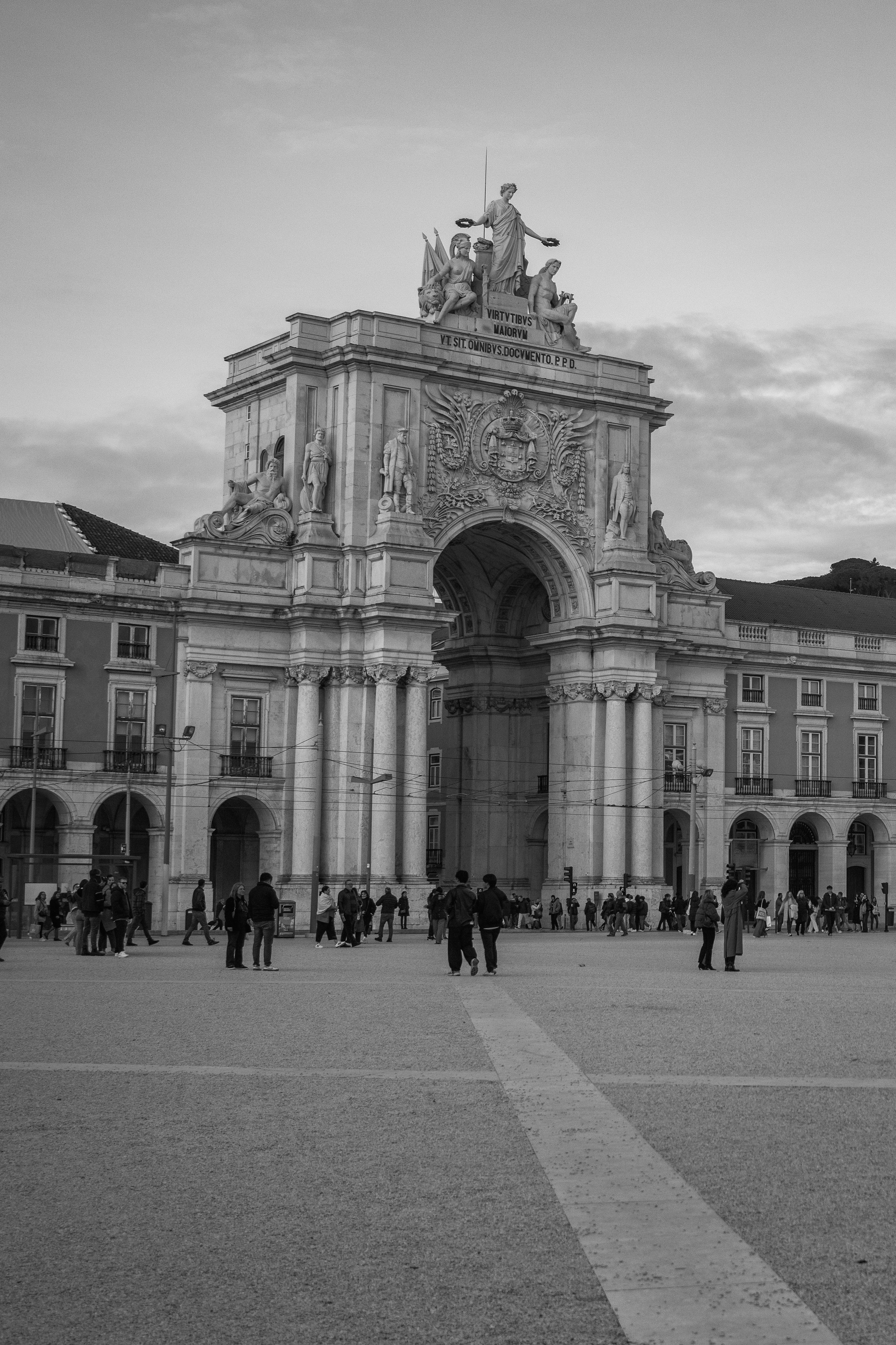 Black and white photo of Arco da Rua Augusta, Lisbon, with people around.