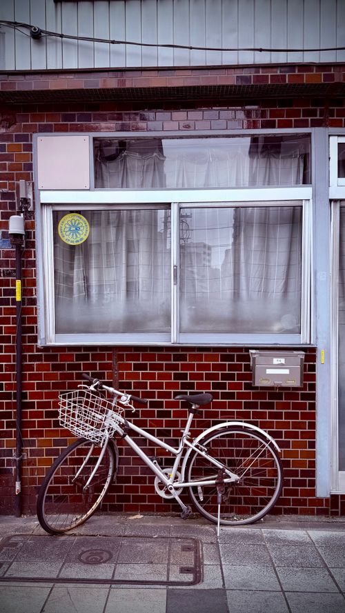 Free A vintage bicycle rests against a red brick wall in Tokyo, Japan, capturing urban charm and simplicity. Stock Photo