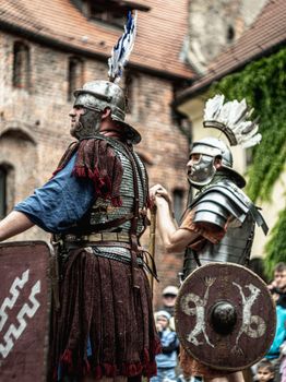 Vivid medieval reenactment featuring Roman soldiers in armor and shields outdoors.